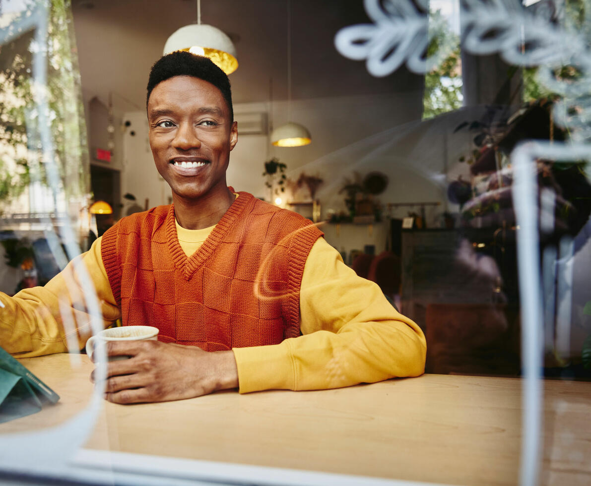 an image of a man having a cup of coffee while smiling 