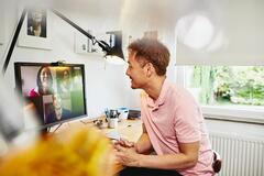 A man working at home and in a virtual meeting