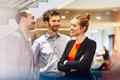 an image of two male coworkers and a female standing and talking