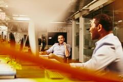 a man conversing with his coworker while in an office cubicle