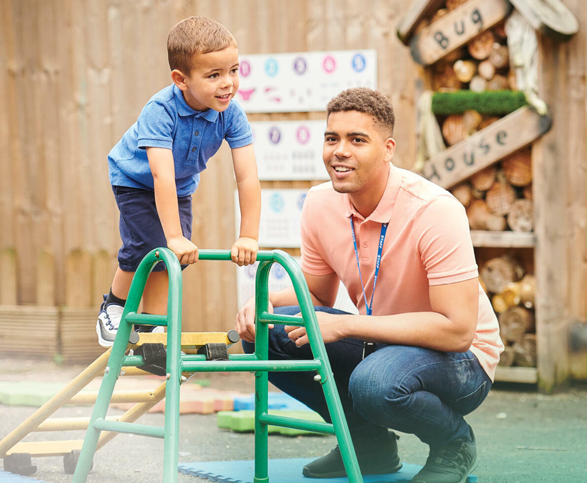 a child in playground with teacher supervising