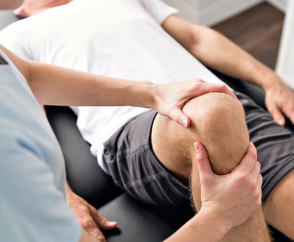 an image of a person helping another with knee pain